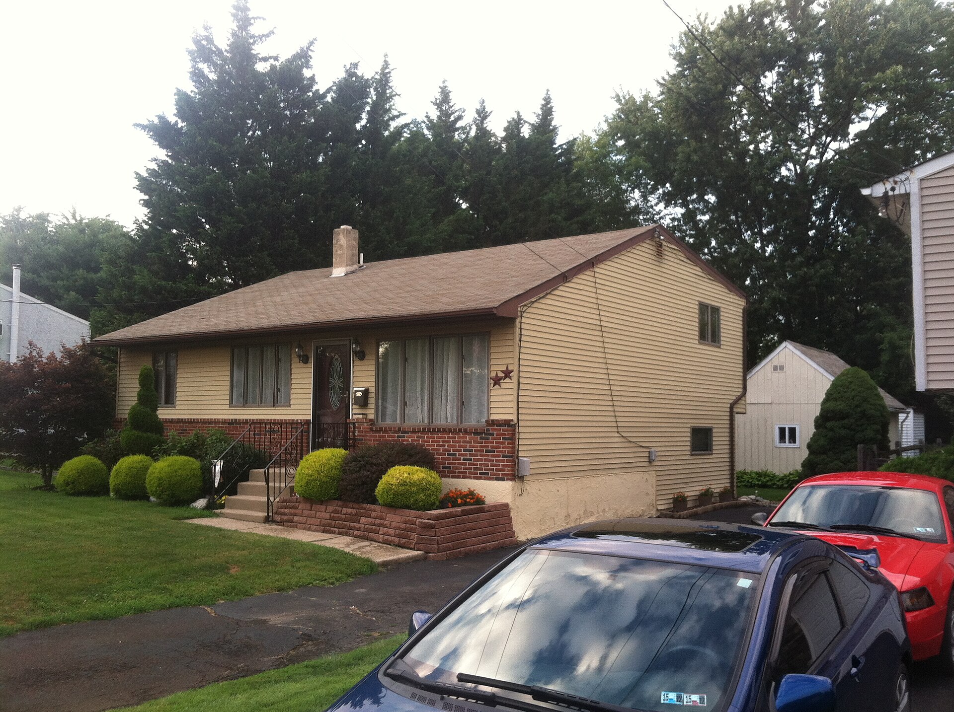 Backsplit house that looks like a one-storey bungalow from the front, with brick base, shrubs and a lawn