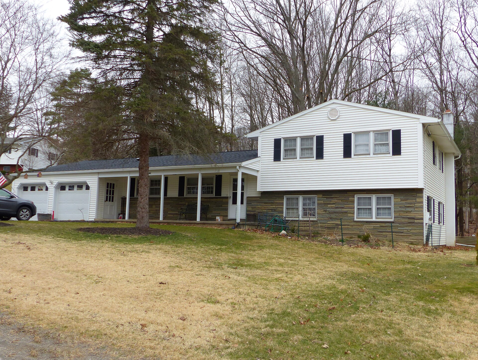 Split-level house with a one-storey garage wing and a raised two-level section with white siding