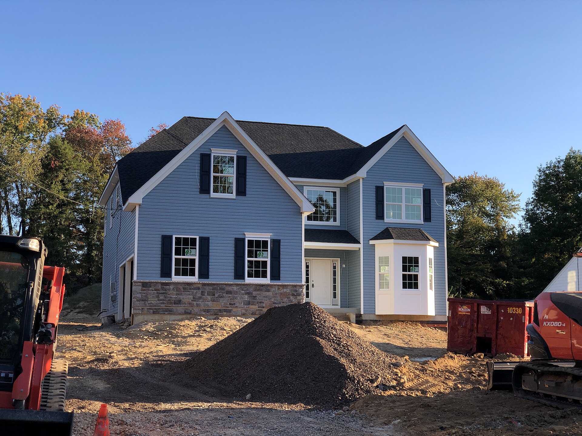 Newly built two-storey house with grey siding and fresh dirt grading before landscaping