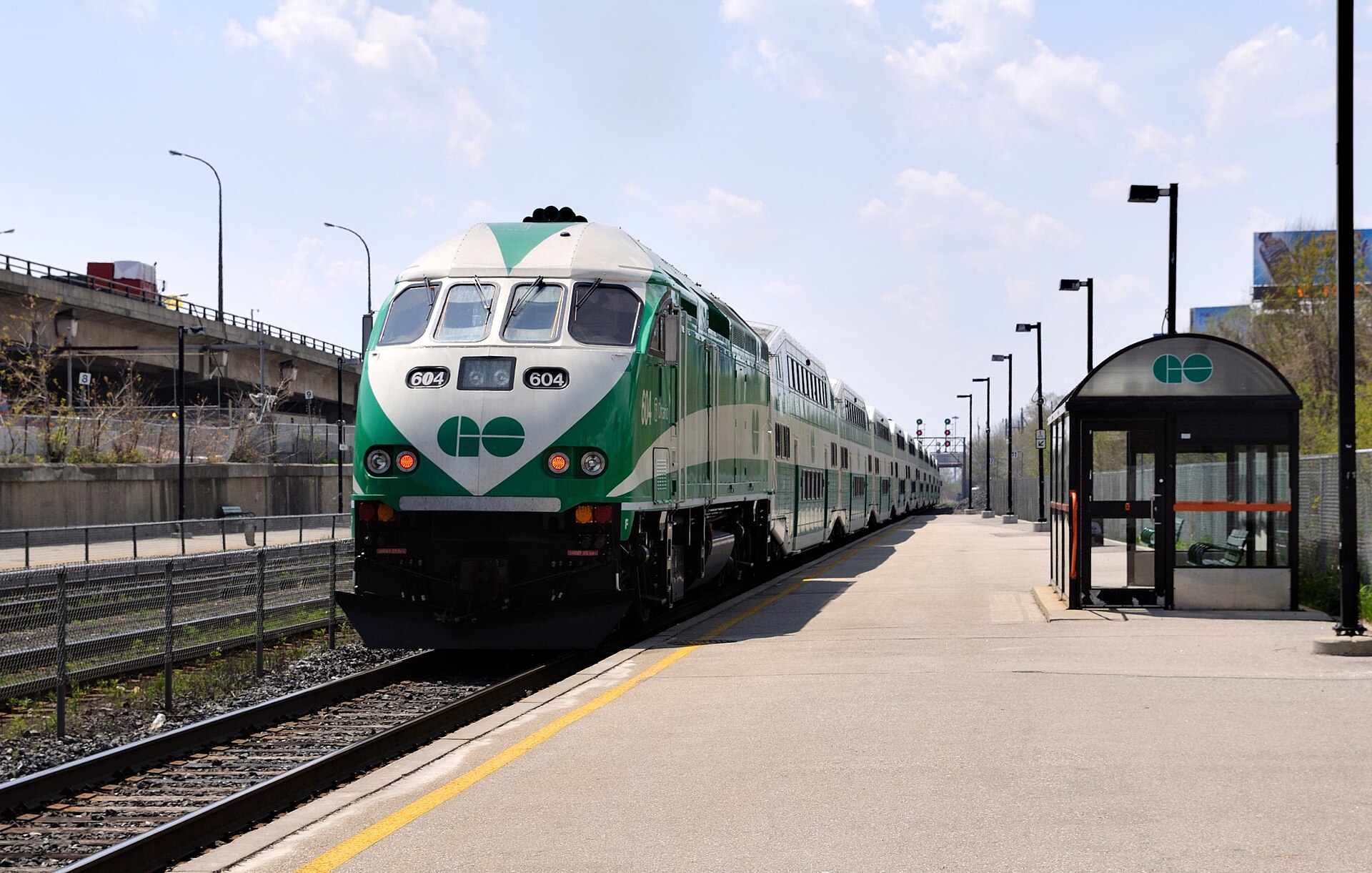 GO Transit commuter train with green and white double-decker coaches stopped at a station platform