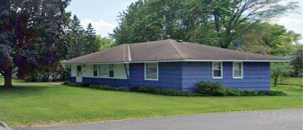 Single-storey ranch-style house with blue siding, a low hip roof and a wide green front lawn