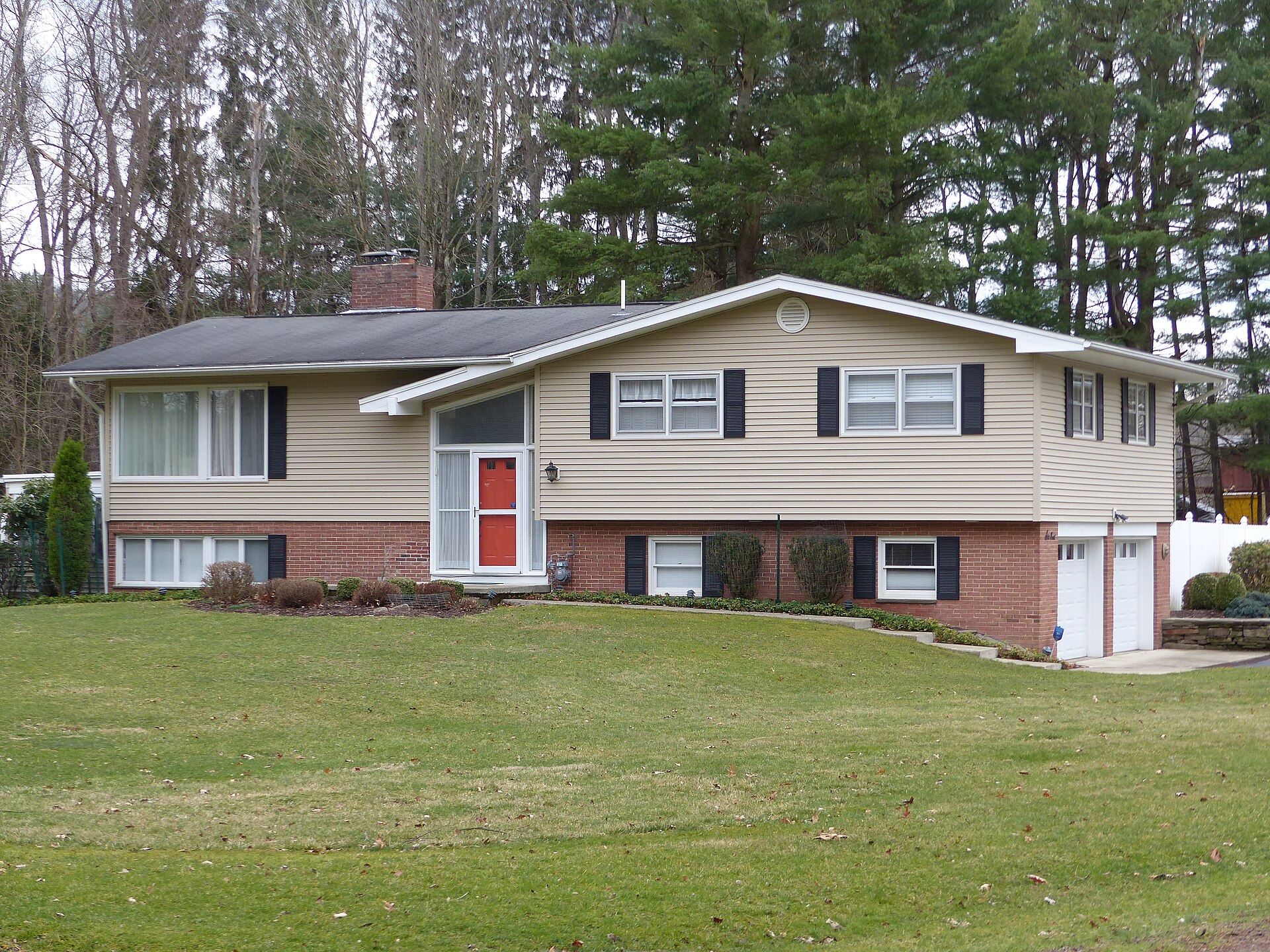 Bi-level raised ranch house with siding, a front entry between levels and a lawn