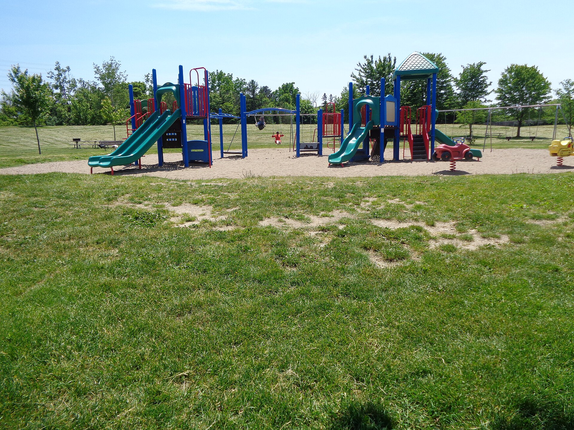 Colourful children’s playground with slides and climbing structures in a grassy park in Mississauga