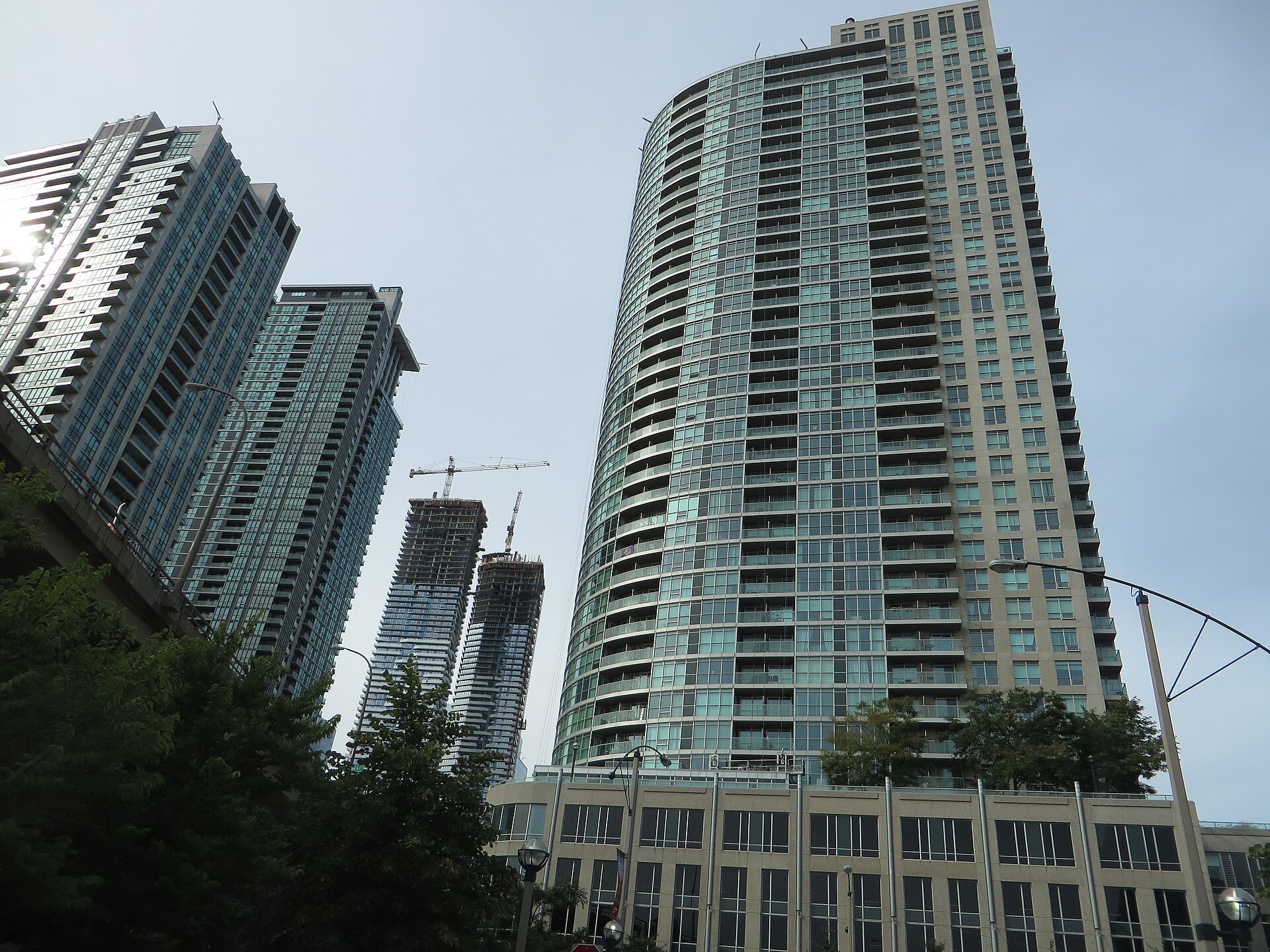 Tall glass condominium towers of the Pinnacle Centre complex rising above trees in downtown Toronto