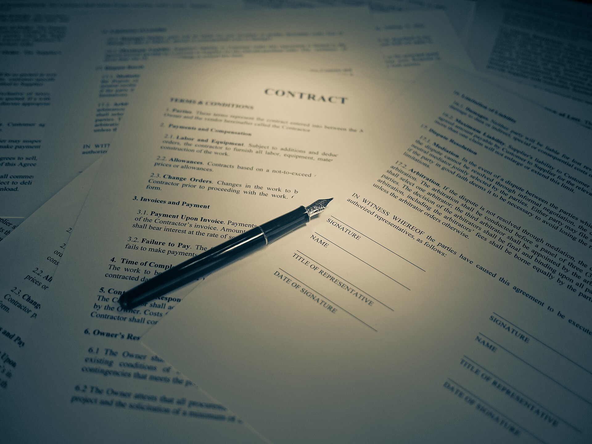 Fountain pen resting on a printed contract document with a signature line