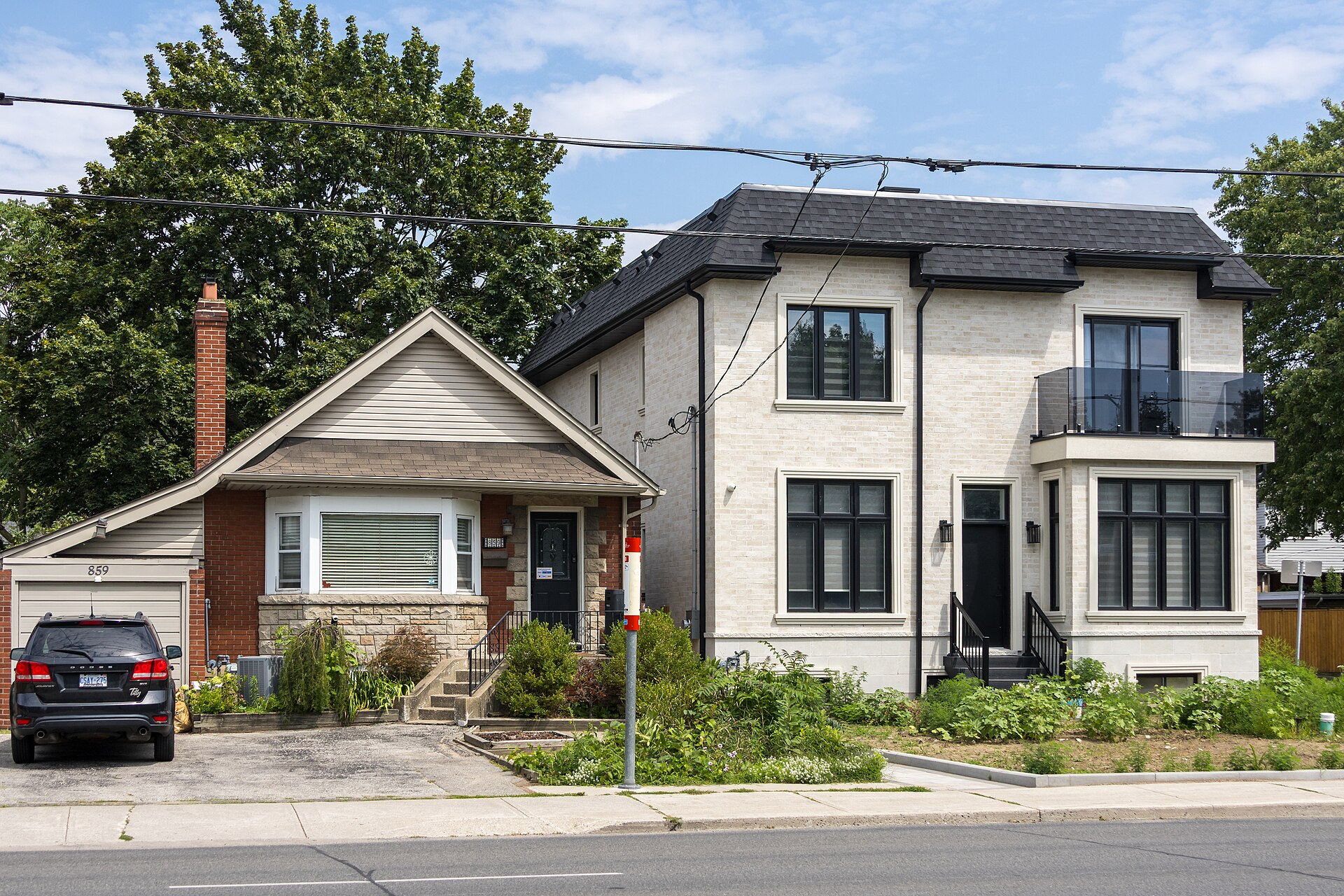 Small early 20th century bungalow beside a much larger new modern infill house on a Toronto street